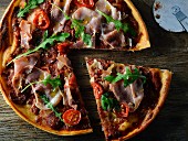 Pizza with Proscuitto, tomato and rocket, sliced