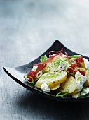Potato salad with onions, ham and goat's cheese