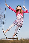 A girl standing on a swing