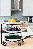 Fresh fruit and vegetables on a plate stand in a kitchen