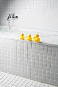 A bubble bath with rubber ducks on side of tub