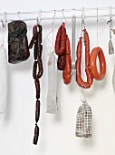 Sausages and raw ham hanging from hooks on a pole
