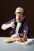 A stereotypical American man with a burger, fries and a cola