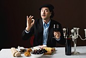 A stereotypical French man with a cheese platter, grapes and red wine