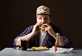 A stereotypical American man eating burger and fries