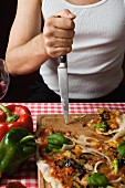 A typical Italian man stabbing his knife into a chopping board next to a pizza
