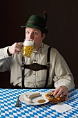 Typisch deutscher Mann in bayerischer Tracht mit Bier und Weisswurst