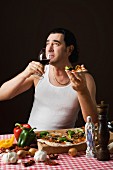 A stereotypical Italian man eating pizza and drinking red wine