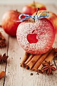 Roter Apfel mit angebissenem Apfel als Muster und Gewürze auf Holztisch