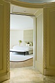 Holzverkleideter traditioneller Durchgang zu elegantem Schlafzimmer mit Designermöbeln in pastellgrünem Farbkonzept