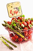 Strawberries and green asparagus in a wire basket with an old-fashioned sign