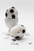 'Fußball-Eier' mit aufgesprühten schwarzen Tupfen in Eierbecher und halb geschält