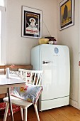 White fifties fridge in dining room with vintage advertising posters in clip-on picture frames on walls