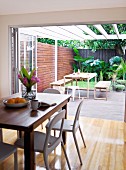 Modern dining area in front of open folding doors leading to terrace