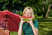 A girl eating a slice of watermelon at a picnic
