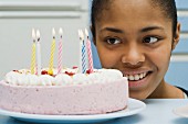 A teenager looking at a birthday cake