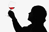 Mann hält ein Glas Rotwein, um es zu prüfen