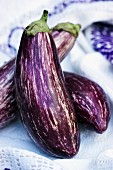 Three aubergines on a tea towel