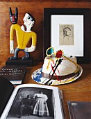 Sunglasses on painted hat, books and painted wooden figurine on table