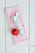 A strawberry and dessert spoons on a pink cloth
