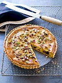 An almond and date tart with pistachios, sliced