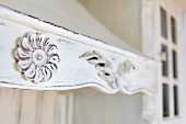 Detail of wooden extractor hood painted white and carved with rosettes