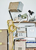 Artistic jumble of vintage lamps and labelled cardboard boxes on shelves
