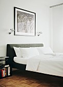Double bed with grey upholstered headboard, white bed linen and Tolomeo wall lamps flanking framed picture