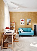 Desk on wooden trestles, Tripp Trapp child's chair, light blue, antique couch in background against vintage-style wall