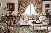Rococo-style ottoman with curved legs, sofa and antiques in front of window with draped curtains in rustic parlour