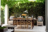 Long dining table and bentwood chairs flanked by wicker chairs on paved, summery terrace