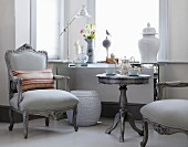 Grey, antique-style armchairs and tea set on matching side table below window