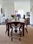 Dark, antique wooden table with matching chairs in open-plan dining area