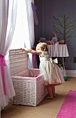 Little girls wearing ruffled dressed opening wicker trunk below window