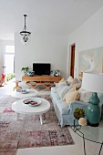 Coffee table with white, amorphous top and pale blue sofa in eclectic, spacious living room