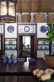 Kitchen counter in front of low installation with doors decorated with blue and white tiles and row of baskets on top