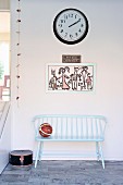 Wooden bench painted pastel blue below child's drawing and station clock on wall