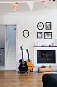 Guitars next to open fireplace below framed family photos in rustic living room