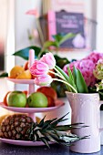Tulips in pink ceramic jug next to cake stand of fruit