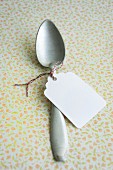 A paper label tied round a silver spoon