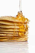 Honey being drizzled onto a stack of pancakes