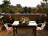 Terrasse mit Holztisch und Metallstühlen, Blick über tropische Landschaft