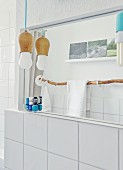Youthful designer lamps, towel rail made from branch and souvenir photos reflected in bathroom mirror