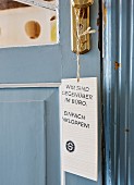 Sign hanging from brass door handle on interior door