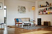 Lounge-Ecke mit Klassiker Stuhl und Sitzbank im Fiftiesstil auf Teppich, in minimalistischem Wohnzimmer