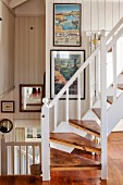 Wooden staircase with white balustrade in open-plan stairwell of beach house