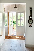 Hallway in Swedish wooden house with half-open French doors and antique barometer on wall