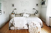 Stummer Diener und Pouf vor Doppelbett, an Kopfende geschnitztes Holzpaneel, weiss lackiert im Elternschlafzimmer