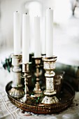 White candles in silver candlesticks on vintage tray