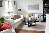 Round, dark wood coffee table on pale rug and sofa set in living room